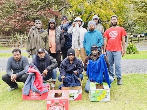 11 RSE workers stand with their warm donated clothing
