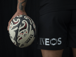 An image of a rugby ball being held next to some shorts with the INEOS logo