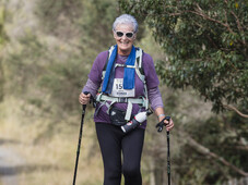 Older woman taking on the course like a boss. Hiking poles and happiness