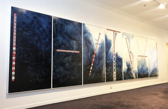 Large scale painting made up of seven panels in gallery space. Predominantly in shades of black and blue with highlights in red and white te reo text and designs