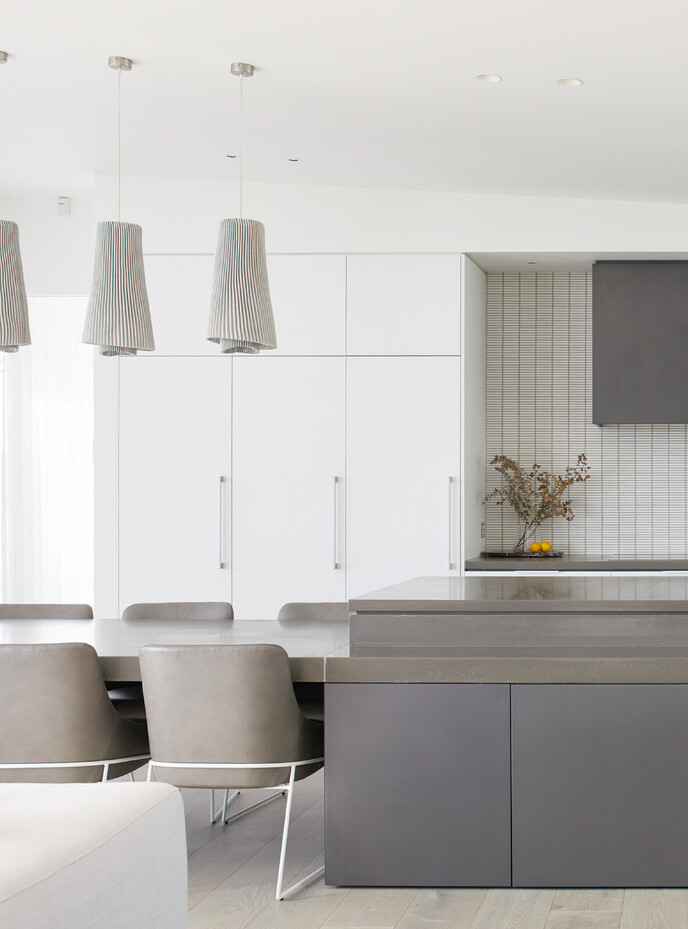 Polished stone kitchen island with extended dining table and modern grey leather chairs