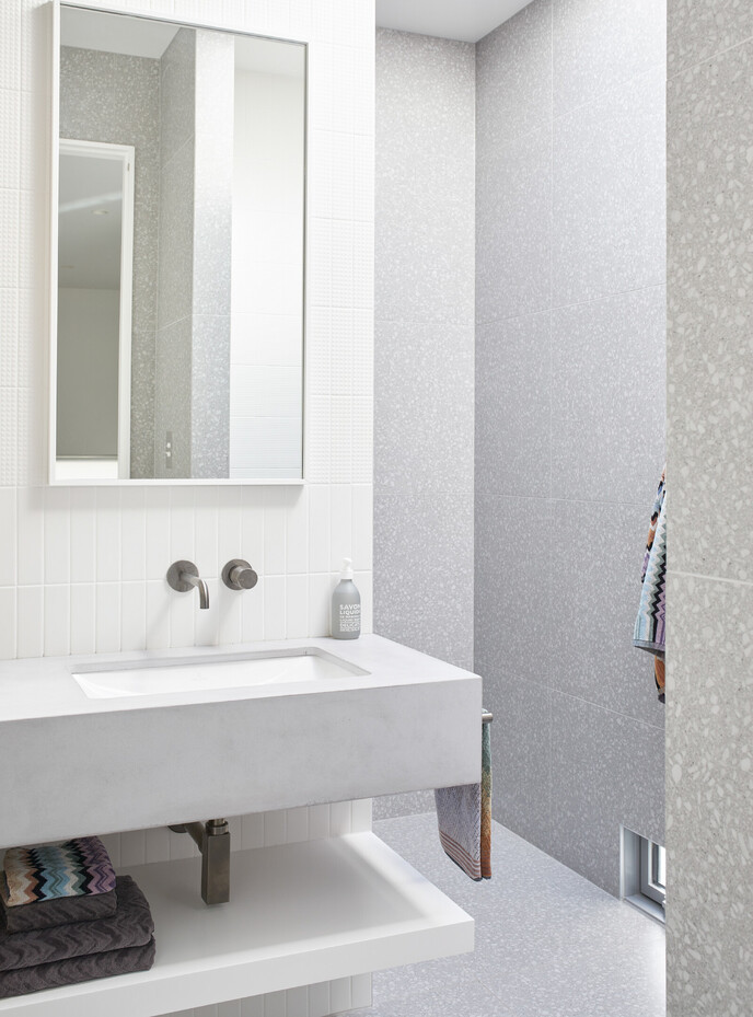 White stone bathroom vanity against white vertical tiles and full height tiled shower