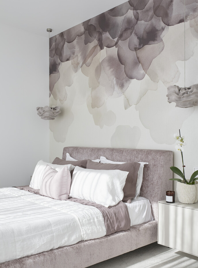 Master bedroom with bold watercolour wallpaper and decorative pendants 