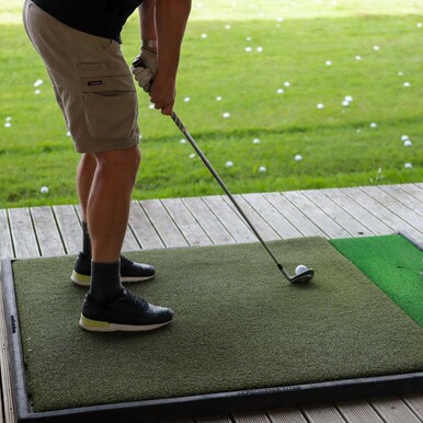 Man with golf club on driving range in Warkworth