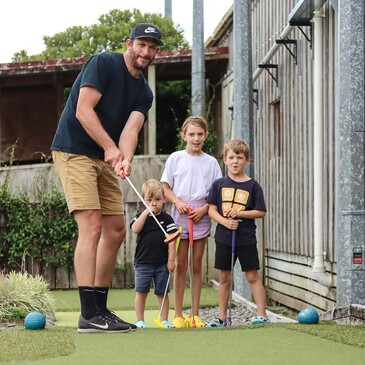 Dad and three kids playing mini golf together