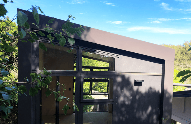 Small building nestled on hillside among trees