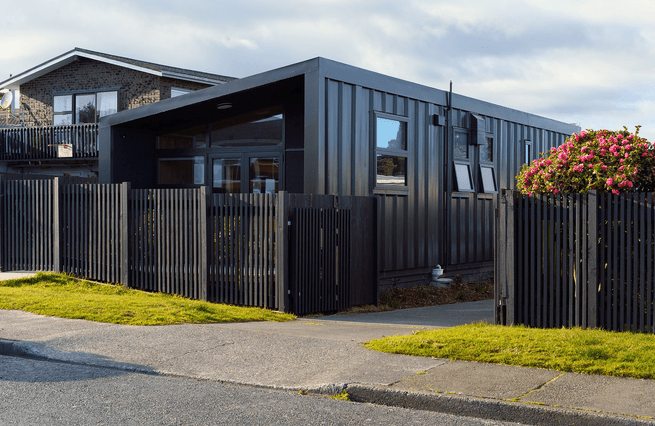 House viewed from street with a black timber fence