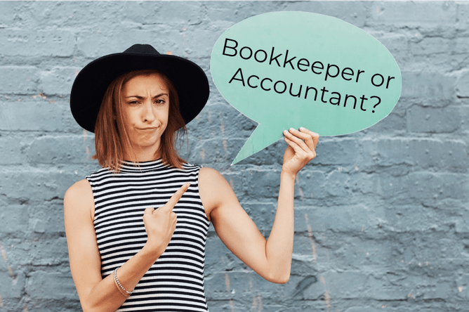 Woman standing in front of a stone wall, striped shirt and black hat, holding a green sign saying Bookkeeper or Accountant?