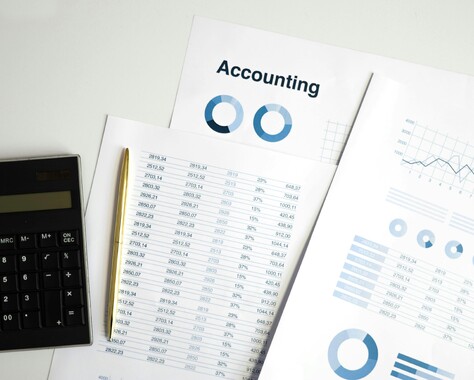 Important Accounting papers with graphs and numbers, calculator and pencil.