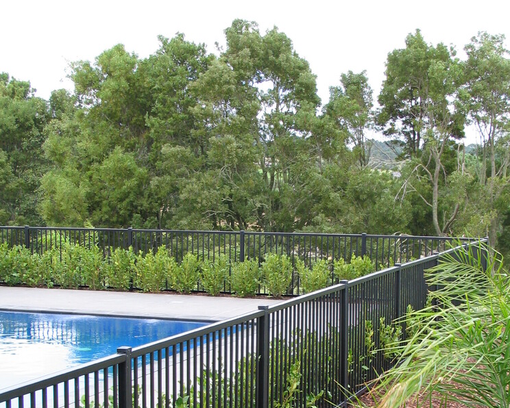photo of a beautiful pool surrounded by garden and trees, as an example of our bar panel fill fencing 