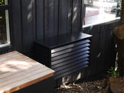 Black Wall hung heatpump cover on bush house. Blending in.