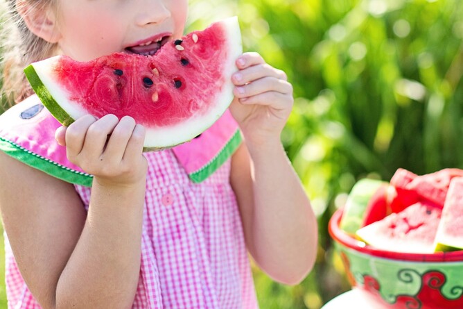 a little child eating a watermelon