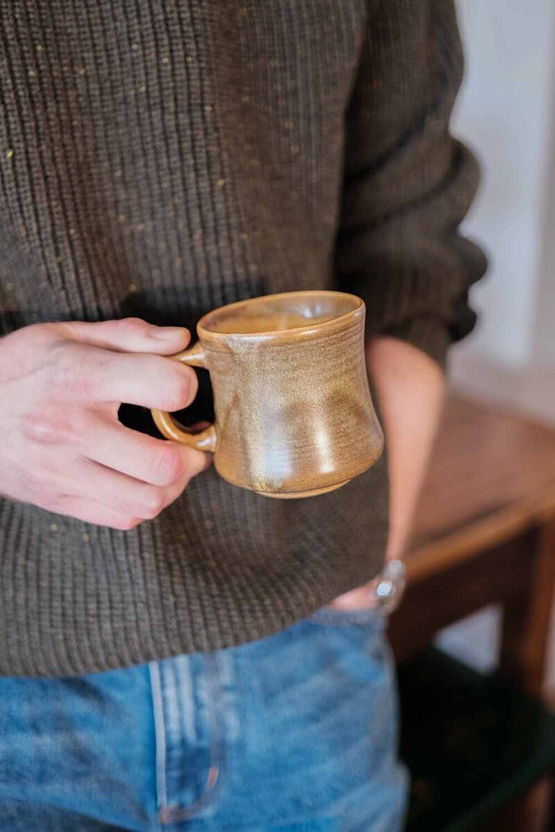 Person holding coffee in a vintage cup, standing in Auckland cafe