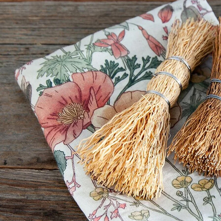 A floral linen table cloth folded and laid on a wooden table
