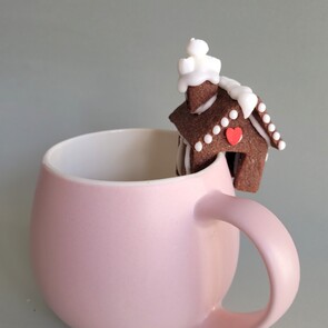 Three gluten-free eclairs in a dish with white squiggly icing on top and pansy flower decoration