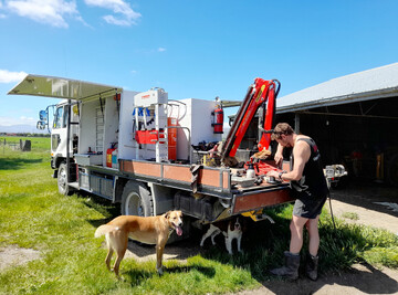 Andy from AEM working onsite in the Maniototo sunshine with cheerful four-legged helpers.