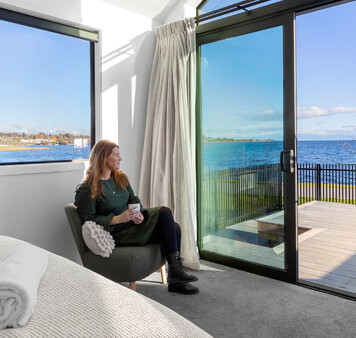 Guest admiring Lake Taupo views from master bedroom at Roam Taupo