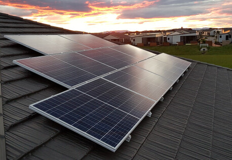 Solar panels on roof in residential area, sunset in background