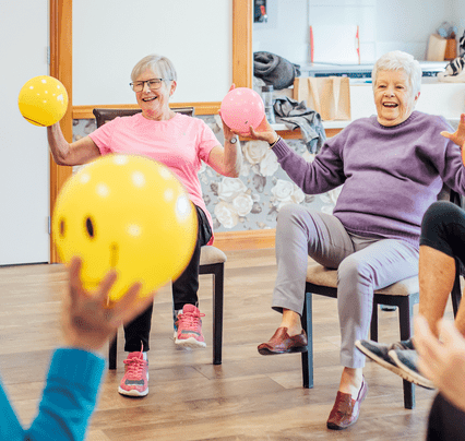 Older women sitting on chairs doing excercise