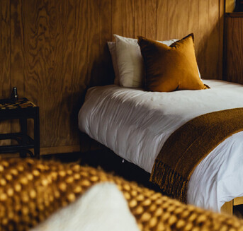 Made up single bed in a whare