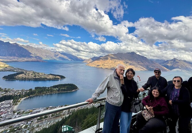 Family at Queenstown gondola lookout with woman in wheelchair enjoying panoramic mountain views