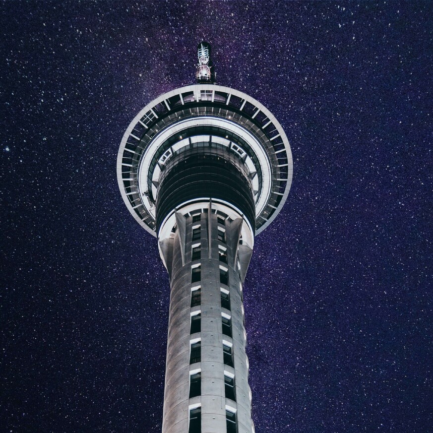 Looking up at Sky Tower at night with stars shining in the sky
