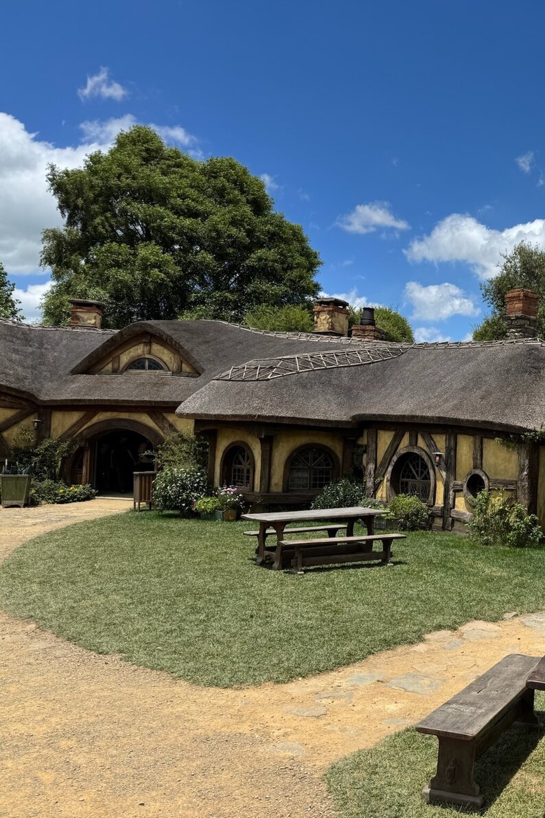 Iconic Hobbiton movie set with round-door hobbit houses nestled in the lush green hills of Matamata, New Zealand.