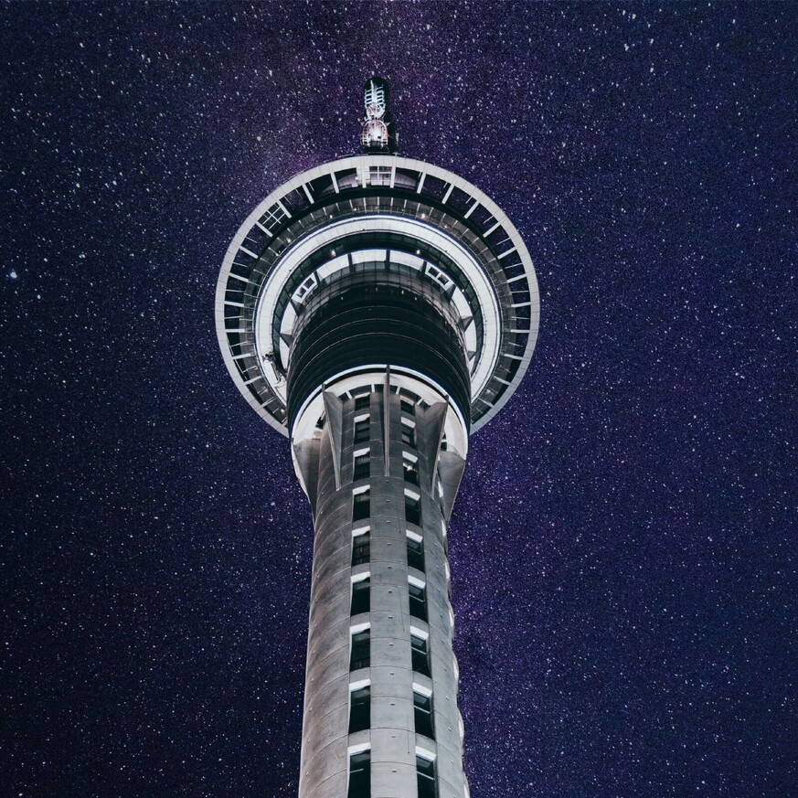 Looking up at Sky Tower at night with stars shining in the sky