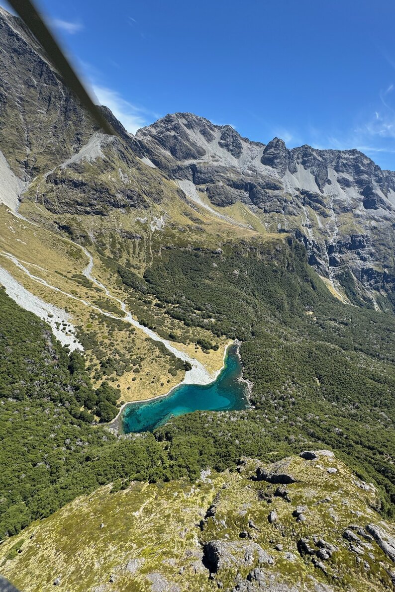 Panoramic view of a glacial valley and alpine lake along the Routeburn Track in New Zealand’s Southern Alps.