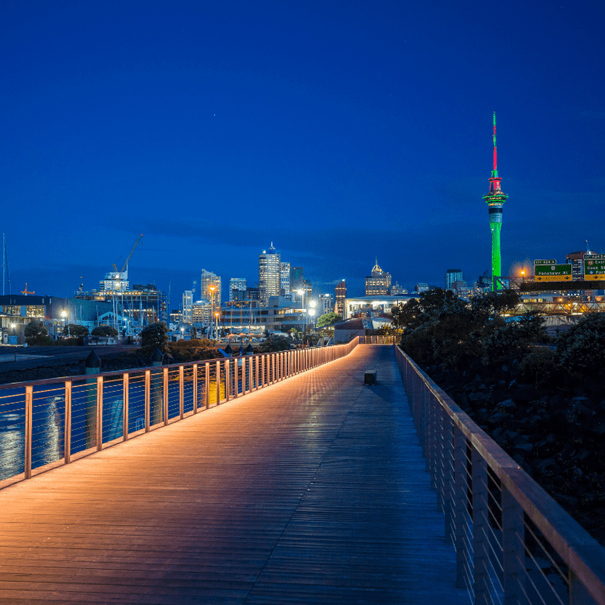 Evening view of a lit-up boardwalk with Sky Tower visible in the background