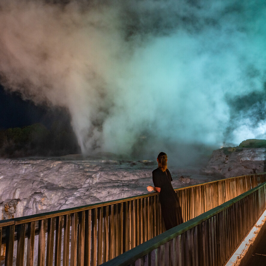 Women watching geysers lit up at night in Rotorua