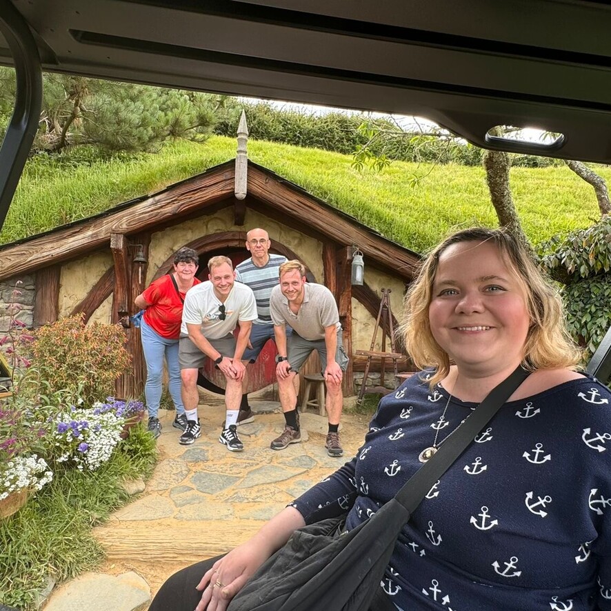 Group of people standing in front of a Hobbiton house in New Zealand