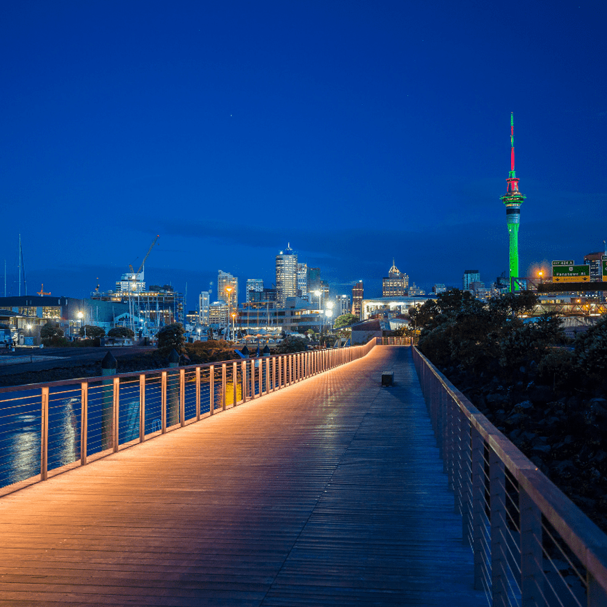 Evening view of a lit-up boardwalk with Sky Tower visible in the background