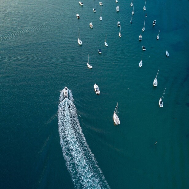Birds eye view of a boat motoring past other boats moored 
