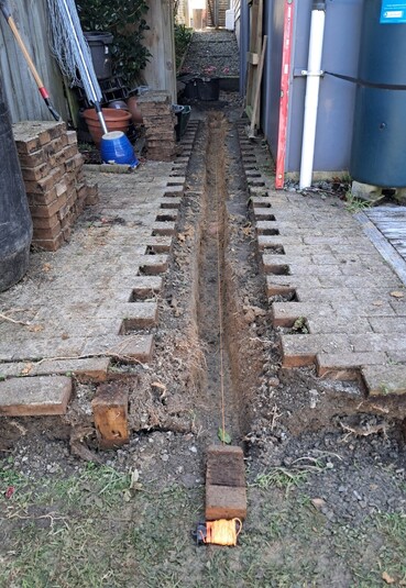 Pavers removed, channel in dirt and string line.