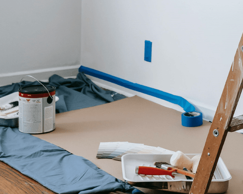 Interior painting equipment - paint, brushes and rollers, a ladder, masking tape and drop cloths. Photo by Blue Bird: https://www.pexels.com/photo/brown-wooden-stepladder-in-a-room-7217924/