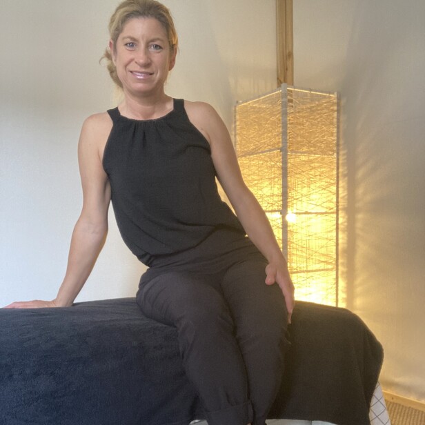 Picture of Sally the massage therapist sitting on the massage table