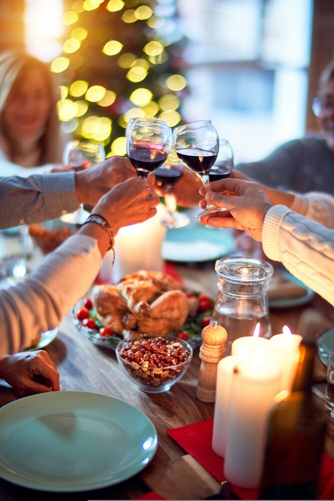 Family raising glasses of wine in a Christmas dinner toast, symbolising togetherness during the holidays