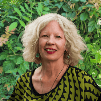 Photo of woman with mid length wavy blond hair in front of brick wall