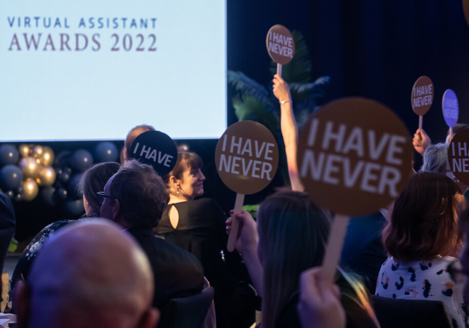Event guests holding up "never have i ever" game signs during Virtual Assistant Awards in Hamilton, NZ.using
