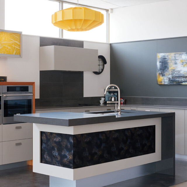 Modern kitchen design with integrated appliances, under-cabinet yellow lighting, functional bar space, and sleek storage solutions, showcased in Barrett Joinery's Timaru showroom, highlighting innovative and functional custom joinery.