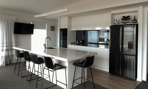 Custom cabinetry with a gloss finish in white, providing a sleek look, crafted by Barrett Joinery.