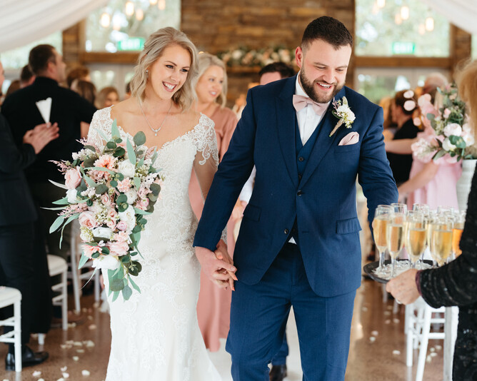 Wedding couple grabbing bubbles after their indoor wedding ceremony at the stone fireplace at Markovina Estate in Kumeu