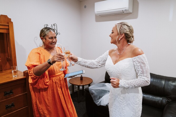 Bride sharing a glass of bubbles with her celebrant in the4 bridal room at Markovina Vineyard Estate in Kumeu