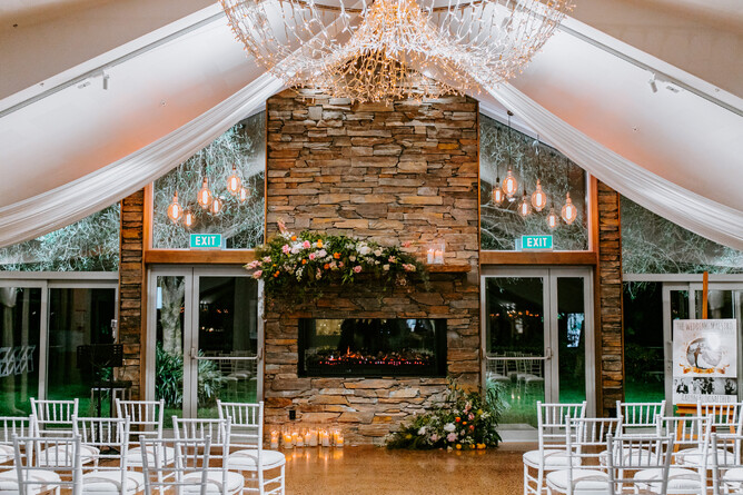 Indoor wet weather wedding ceremony setup at stone fireplace at Markovina Estate in Kumeu