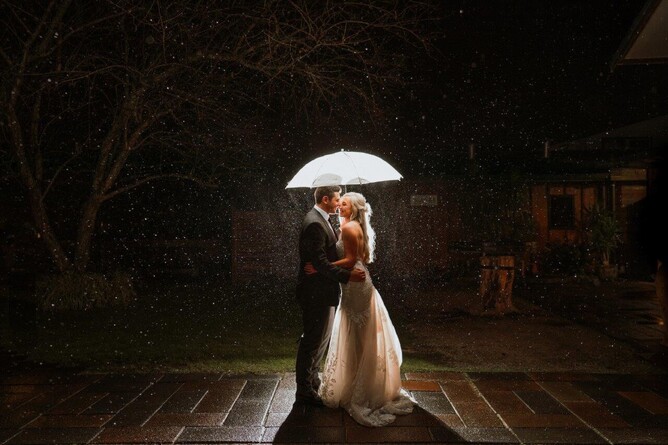 Bridal Couple taking night photo in rain at Markovina Vineyard Estate in Kumeu