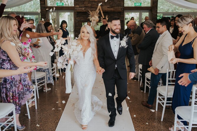 Bride & Groom walking down the aisle at their indoor wedding ceremony at the stone fireplace at Markovina Estate in Kumeu