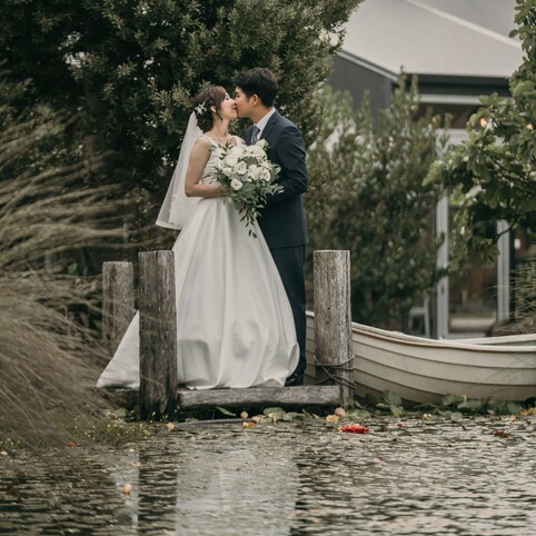 bride and groom kissing by the rowboat