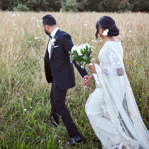 wedding couple walking through a field