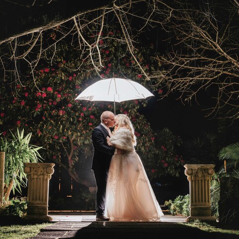 bride and groom posing with umbrella